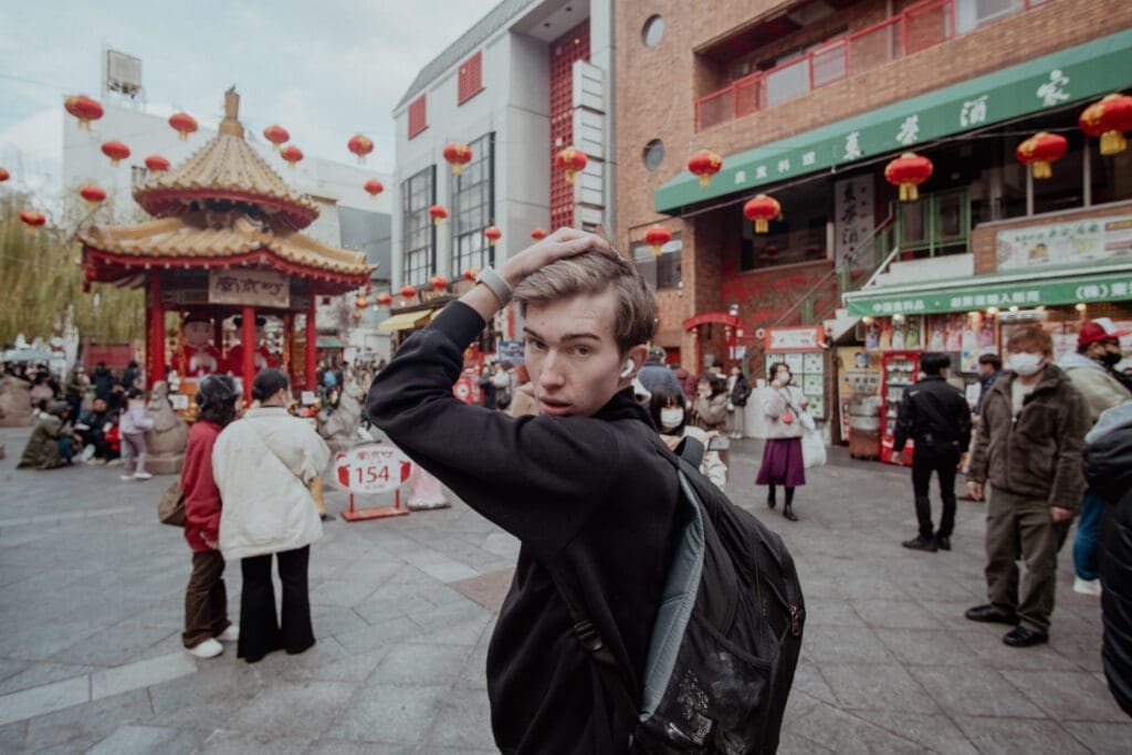 In a busy market in Kobe, Japan, Noah uses headphones to drown out the noise and to reflect on his solo trip. Music is essential for a solo trip.