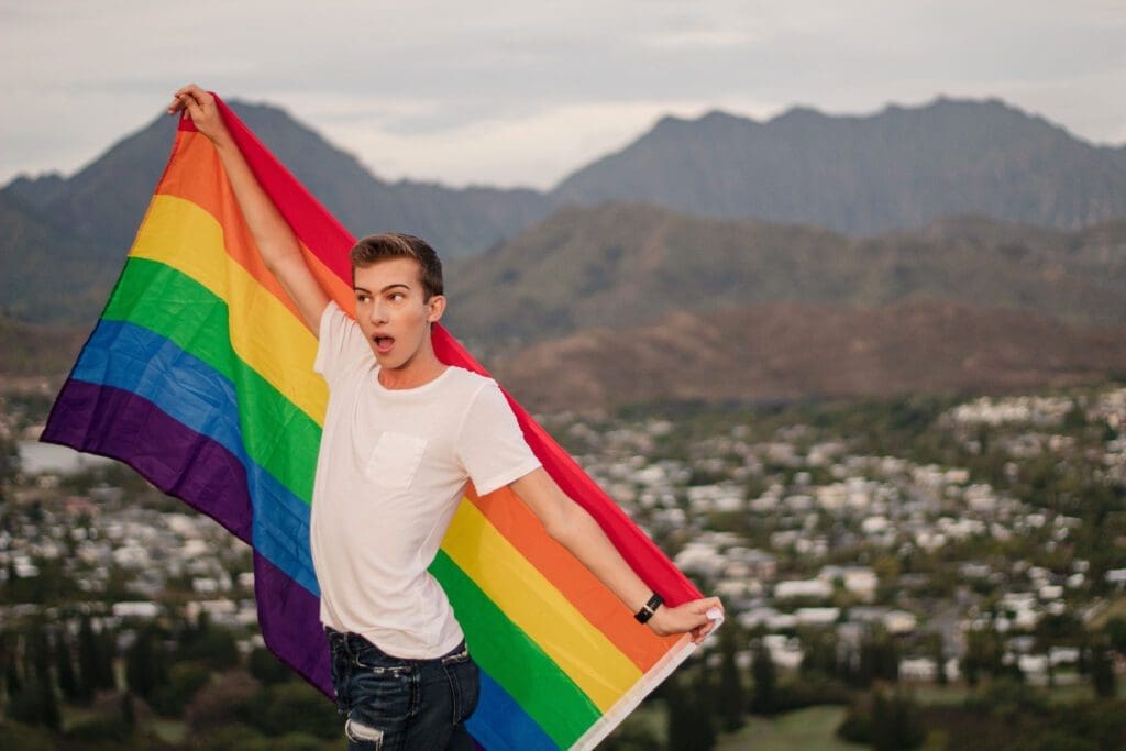 Noah takes the world poses with a pride flag on a hike. 