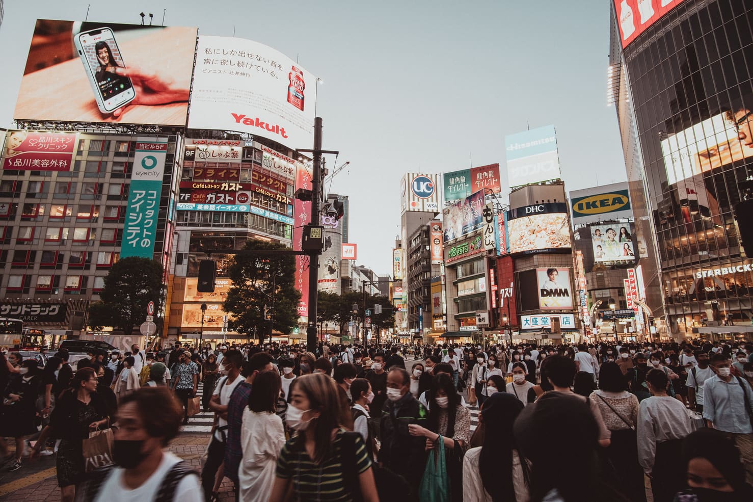 Thousands of people cross the Shibuya Crossing at dusk. 