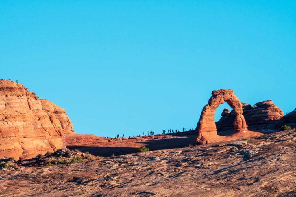 Crowds gather to watch the sunrise at Delicate Arch in Arches National Park. 