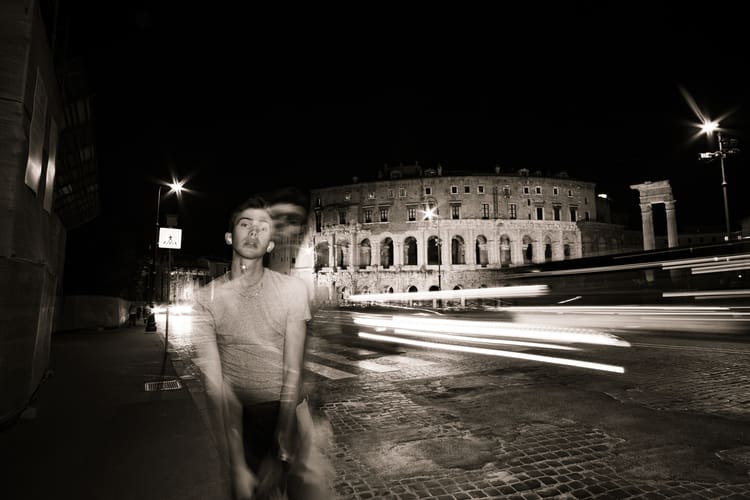 Noah stands in the street in Rome to take an exciting travel photo.